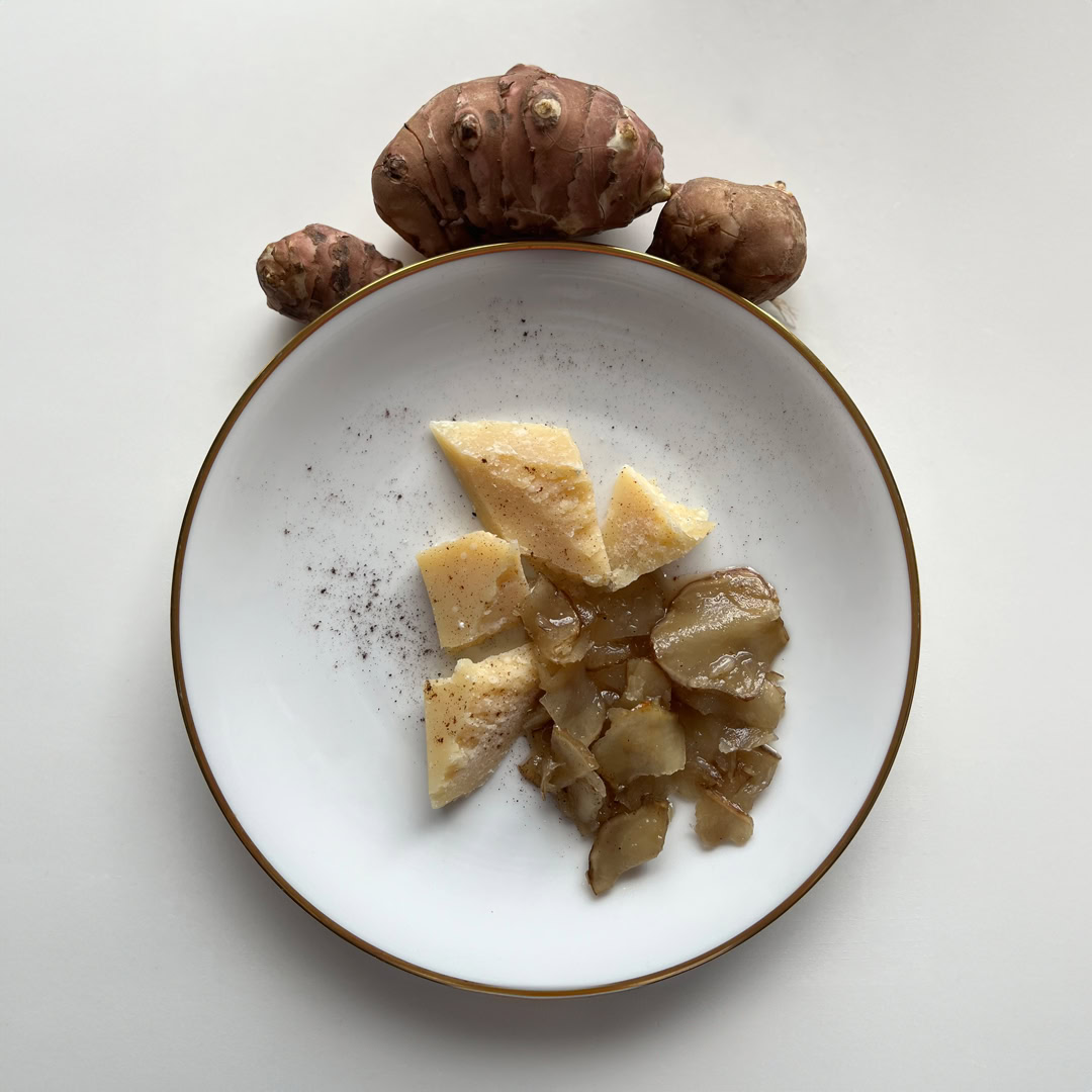 Antipasto con topinambur, formaggio e spezie su piatto bianco.