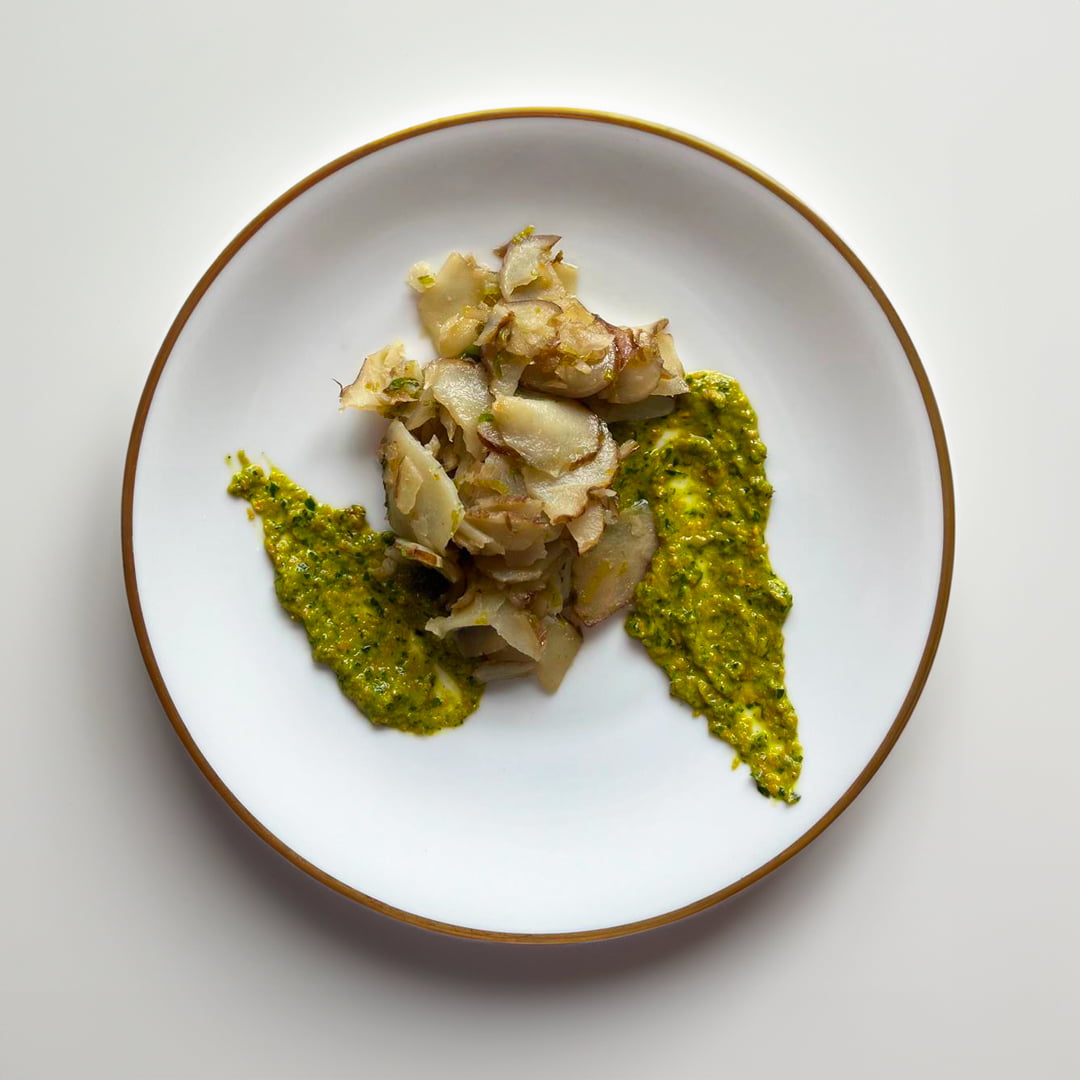 Risotto con topinambur e funghi porcini su piatto bianco.