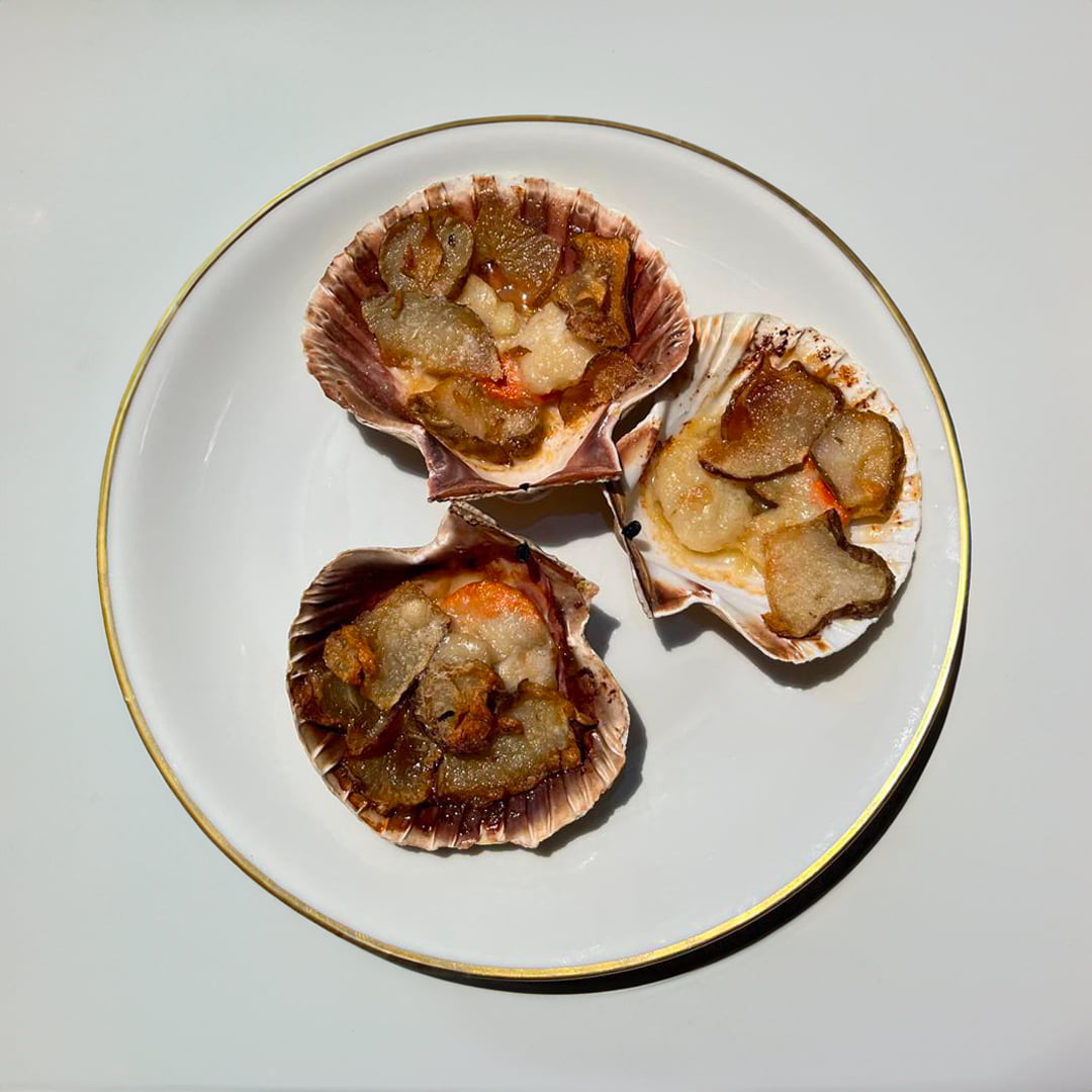 Cozze ripiene con ripieno di mare su piatto bianco elegante.